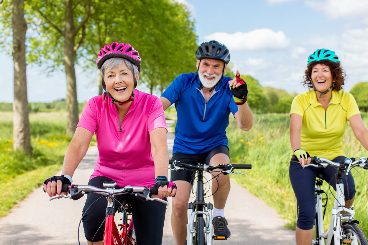 Joyful Seniors Cycling Together on a Sunny Pathway with Lush Greenery Surroundings